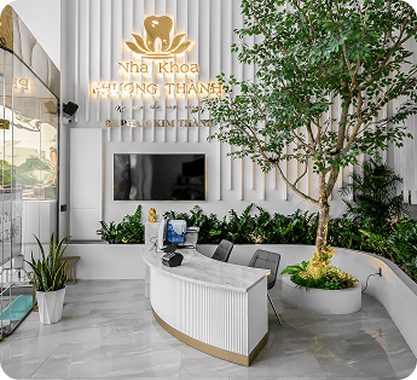 Quầy lễ tân hiện đại của Nha Khoa Phương Thành với thiết kế sang trọng, cây xanh trang trí, màn hình TV và logo nha khoa nổi bật tạo cảm giác chuyên nghiệp và thân thiện.